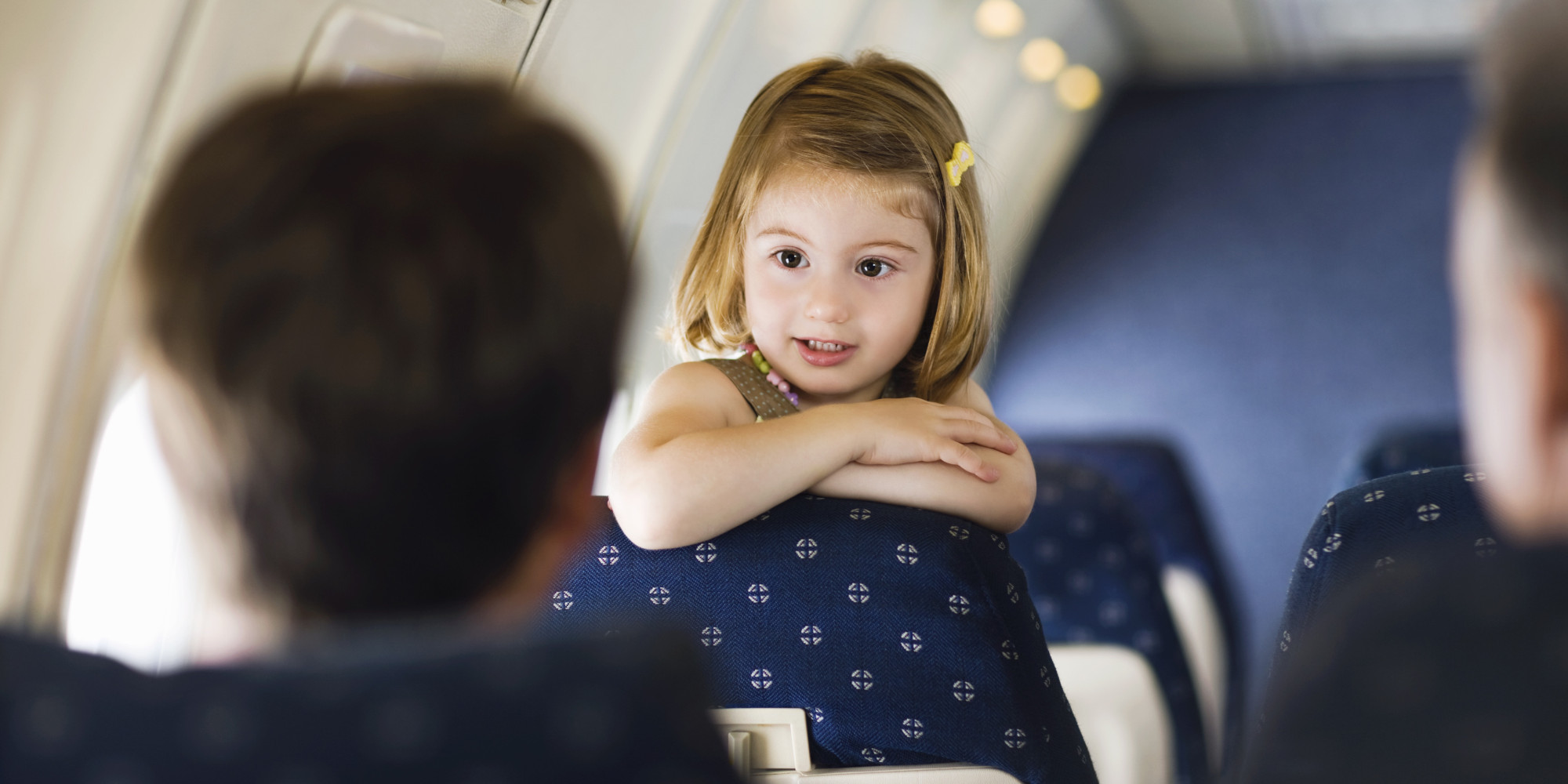 young girl leaning over seat talking to adults
